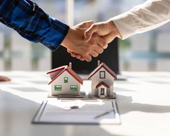 Real estate agents shake hands after the signing of the contract agreement is complete.